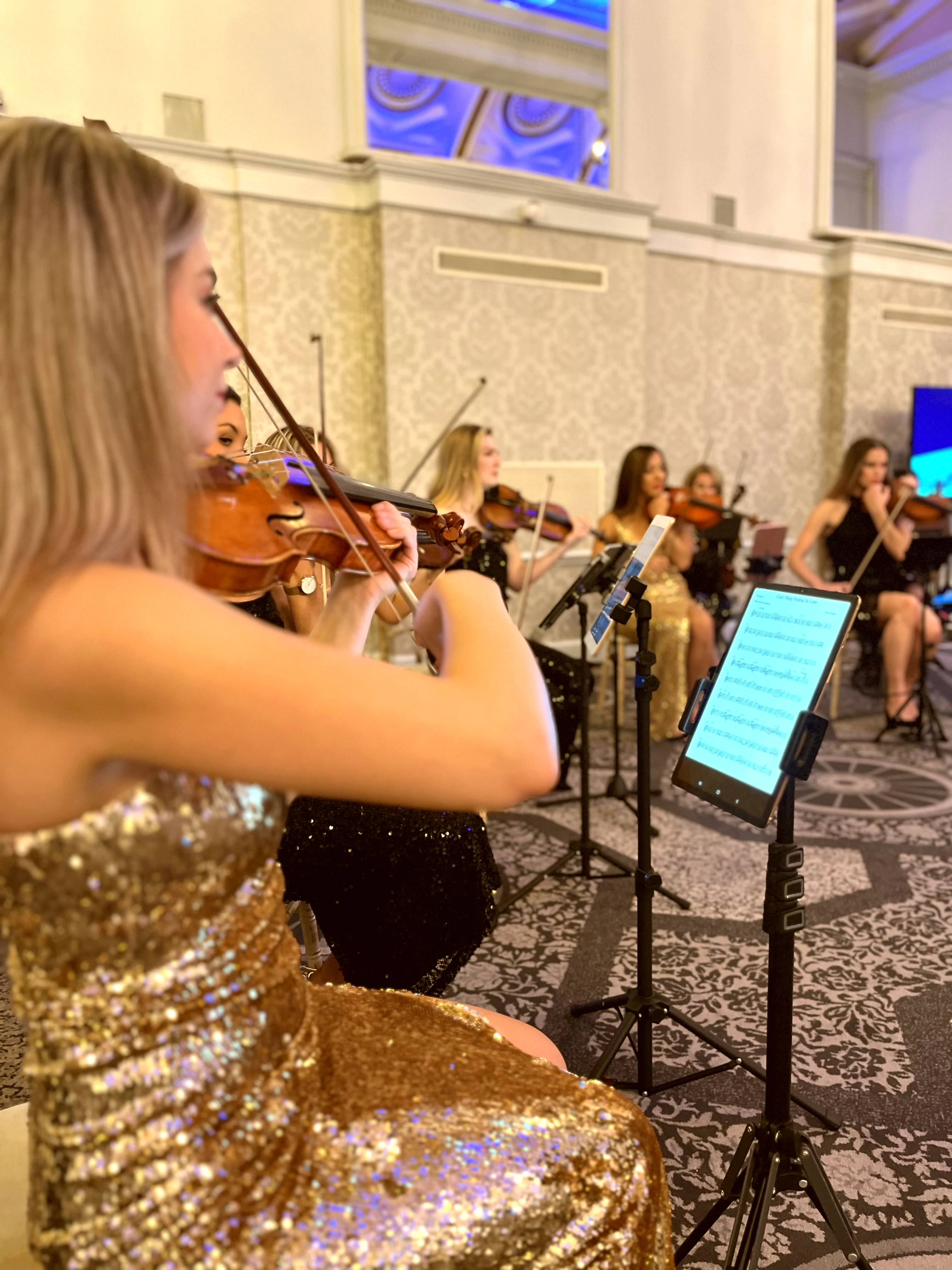 Close-up of violinist in gold dress performing with the pop string orchestra