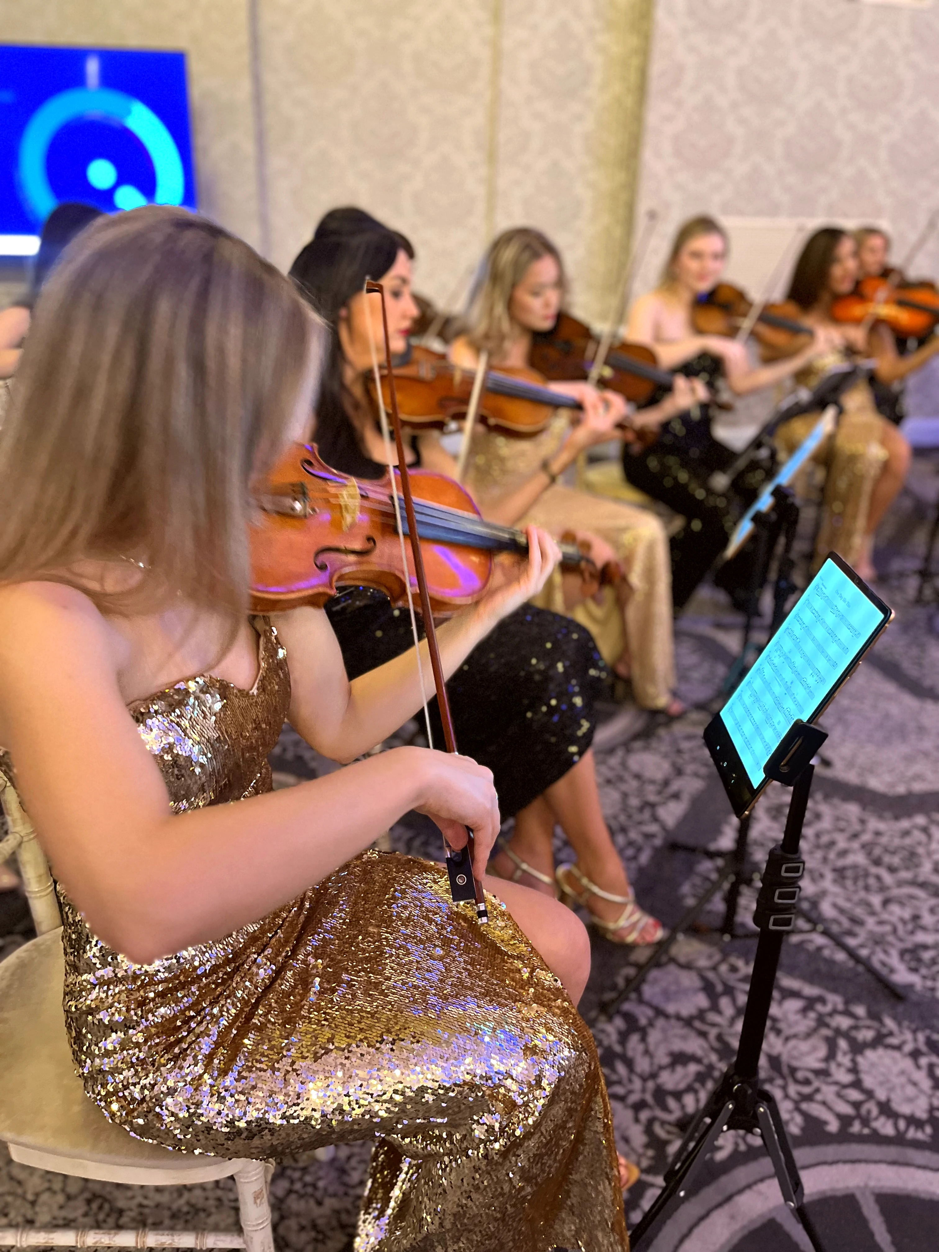 Violinist in gold sequin gown leading the pop string orchestra