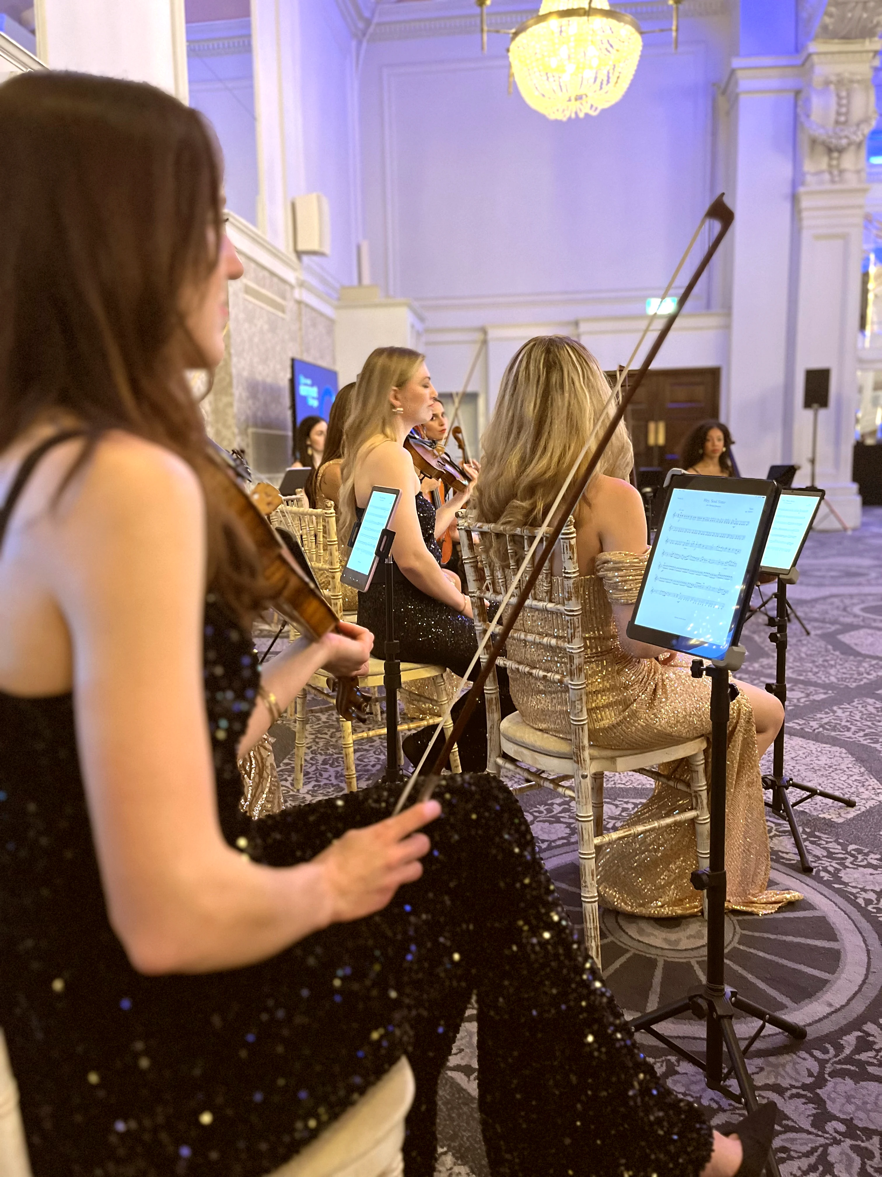 String orchestra performers in a London venue with blue ambient lighting